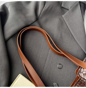 Detail of dark brown woven leather tote showing texture and long shoulder straps