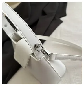 Close-up of premium silver-tone hardware and fine stitching on a white leather handbag