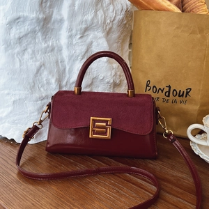 Elegant wine red matte leather crossbody bag with gold buckle on wooden surface