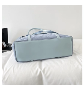 Detail view of reinforced bottom and textured blue fabric of a large travel tote bag