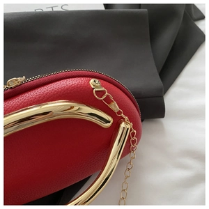 Detail of red pebbled leather bag with gold handles and chain strap close-up