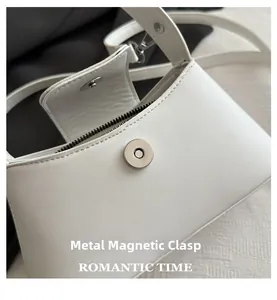 Close-up of the silver magnetic metal clasp on this white French style leather baguette bag