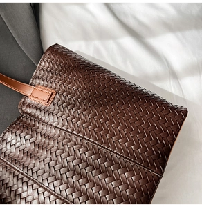 Detailed close-up of dark brown woven leather texture on a stylish tote shoulder bag