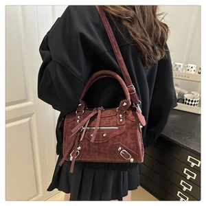 Detailed view of burgundy suede crossbody bag with iconic silver studs and long tassels