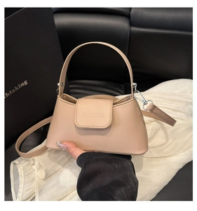 Detail of light apricot faux leather handbag with embossed logo and silver metal hardware