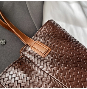 Detail of dark brown woven leather texture and sturdy handle stitching on tote bag
