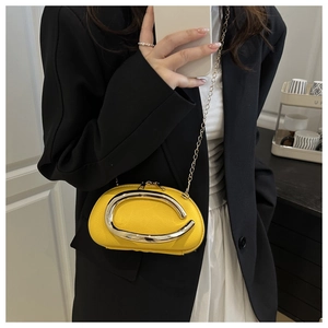 Close-up of bright yellow mini leather bag with large silver C-shaped metal decoration