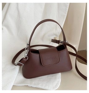 Detail of a chocolate brown leather handbag featuring embossed logo and silver hardware