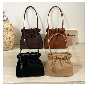 Detail view of four pleated suede bucket bags in coffee, caramel, black, and beige colors