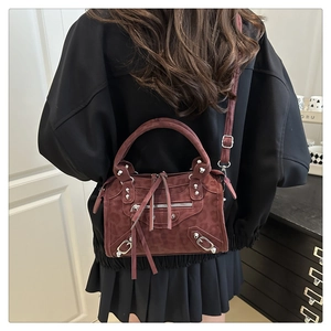 Detail of dark burgundy suede motorcycle bag with leopard pattern and silver rivets