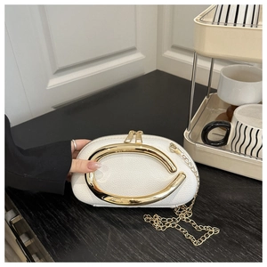Detailed close-up of white lychee leather handbag with a large C-shaped gold metal handle