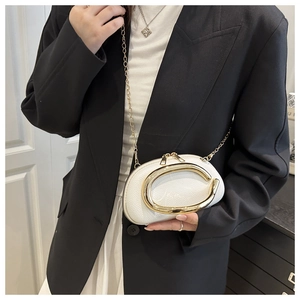 Macro detail of white pebble leather bag with oversized gold metal C-clasp and chain strap