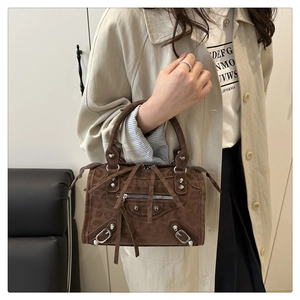 Detail of dark brown suede crossbody bag with silver rivets and decorative long tassels