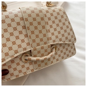 Close-up of beige faux leather with clover monogram print and gold-tone metal hardware