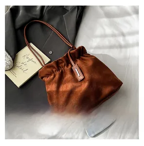 Detail of tan suede bucket bag with pleated drawstring and stylish metal charm decoration