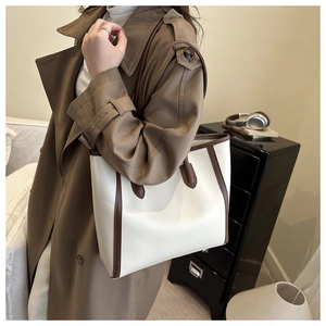 Detail of a large capacity two-tone tote bag in white and brown leather on a sofa