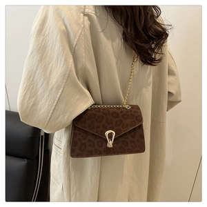 Detail view of leopard print crossbody bag with gold horseshoe buckle and chain strap