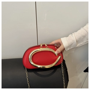 Detail of red lychee textured leather evening bag with large round gold metal handle