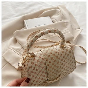 Close-up of vintage printed leather texture and gold metal hardware on crossbody bag