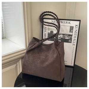 Detail of a dark brown suede tote bag featuring unique thick woven shoulder straps