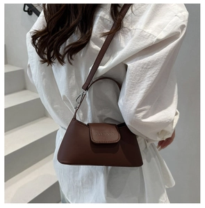 Brown leather baguette bag with detachable strap shown in a minimalist scene