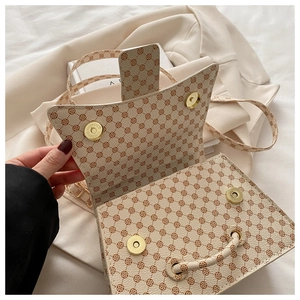 Detail view of beige crossbody bag showing secure golden magnetic clasps and floral pattern
