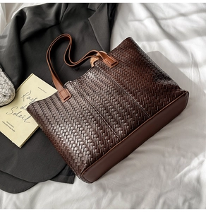 Detail of dark brown woven tote bag with leather texture on a white fabric background