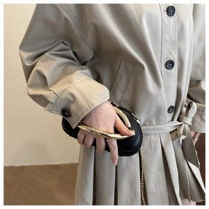 Detail of lychee pattern black leather clutch with wide gold polished metal ring handle