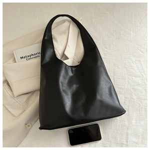 Close-up of black minimalist tote bag on neutral blazer with high-quality PU leather texture