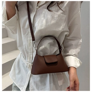 Detail of a dark brown matte leather bag with top handle and embossed logo on the flap