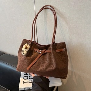Vintage leopard print suede tote bag with brown straps and plush charm on black sofa
