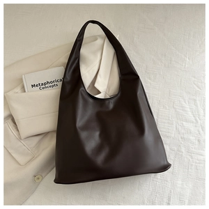 Detail of minimalist dark coffee shoulder bag with premium leather texture and hobo shape
