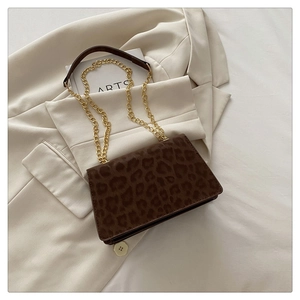 Detail of leopard print crossbody bag with gold chain strap on a white blazer background