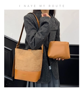 Detail of caramel brown suede and leather bucket bag with a matching clutch and gold text