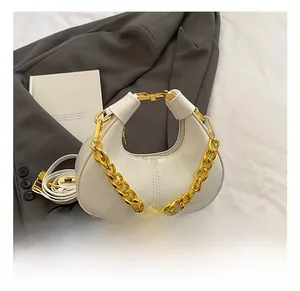 Detail of white patent leather mini dumpling bag with chunky gold chain handle