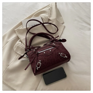 Detail of wine red leopard embossed handbag with silver studs and tassel on beige blazer