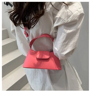 Pink baguette bag shown on shoulder in a minimalist indoor staircase setting