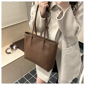 Mirror selfie showing a caramel brown leather tote bag with minimalist stitching details