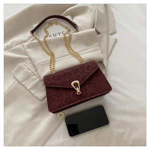 Detail of burgundy leopard embossed crossbody bag with gold chain and metal buckle