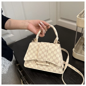 Detail of beige letter print handbag with gold hardware and removable shoulder strap