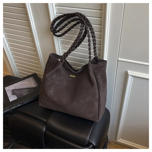 Detail of braided shoulder strap and gold logo on chocolate suede tote bag