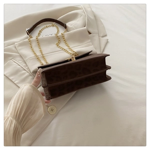 Detail of leopard print crossbody bag with gold chain strap and twist lock closure