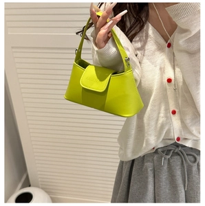 Close-up of fluorescent yellow leather handbag with flap cover and brand embossing