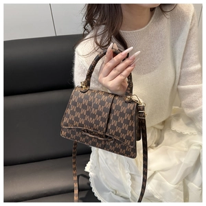 Detailed view of brown leather bag with all-over M pattern and gold metal hardware