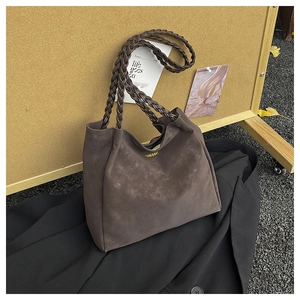 Detail of dark coffee tote bag featuring braided handle and matte leather texture