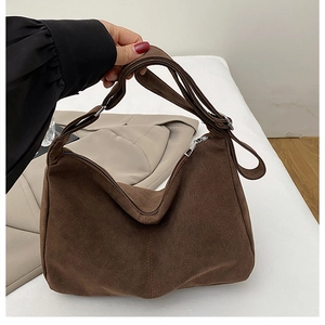 Detail of dark brown suede tote bag with silver zipper and wide shoulder strap