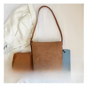 Detailed top view of brown suede bucket bag set with matching inner pouch on white fabric
