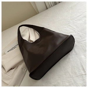 Detail of dark brown leather tote bag showing structured base and premium texture