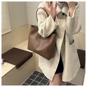 Close-up of a large dark brown leather tote bag worn by a model in a minimalist mirror selfie