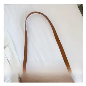 Detail of adjustable brown suede shoulder strap with a metallic buckle on minimalist bag